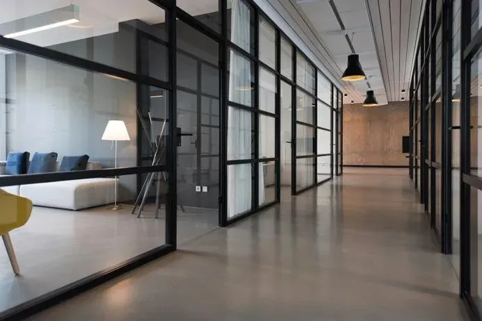 Glass-partitioned office corridor with clean floors and workspaces